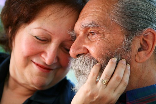 Une femme et un homme âgés ont leur tête l'une contre l'autre et sourient avec tendresse.