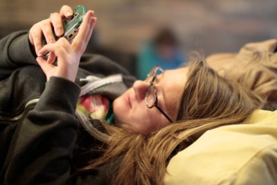 Une jeune femme, allongée sur son lit avec son smartphone, essaie de trouver les mots pour répondre négativement à un message sur un site de rencontre