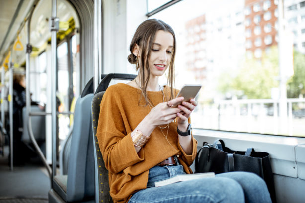 Une jeune femme utilise la messagerie instantanée de son téléphone, dans un tramway.