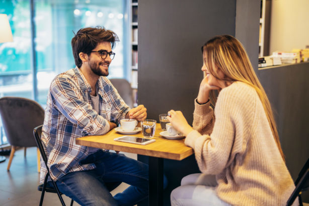 Deux célibataires souriants se rencontrent pour la première fois dans un café.