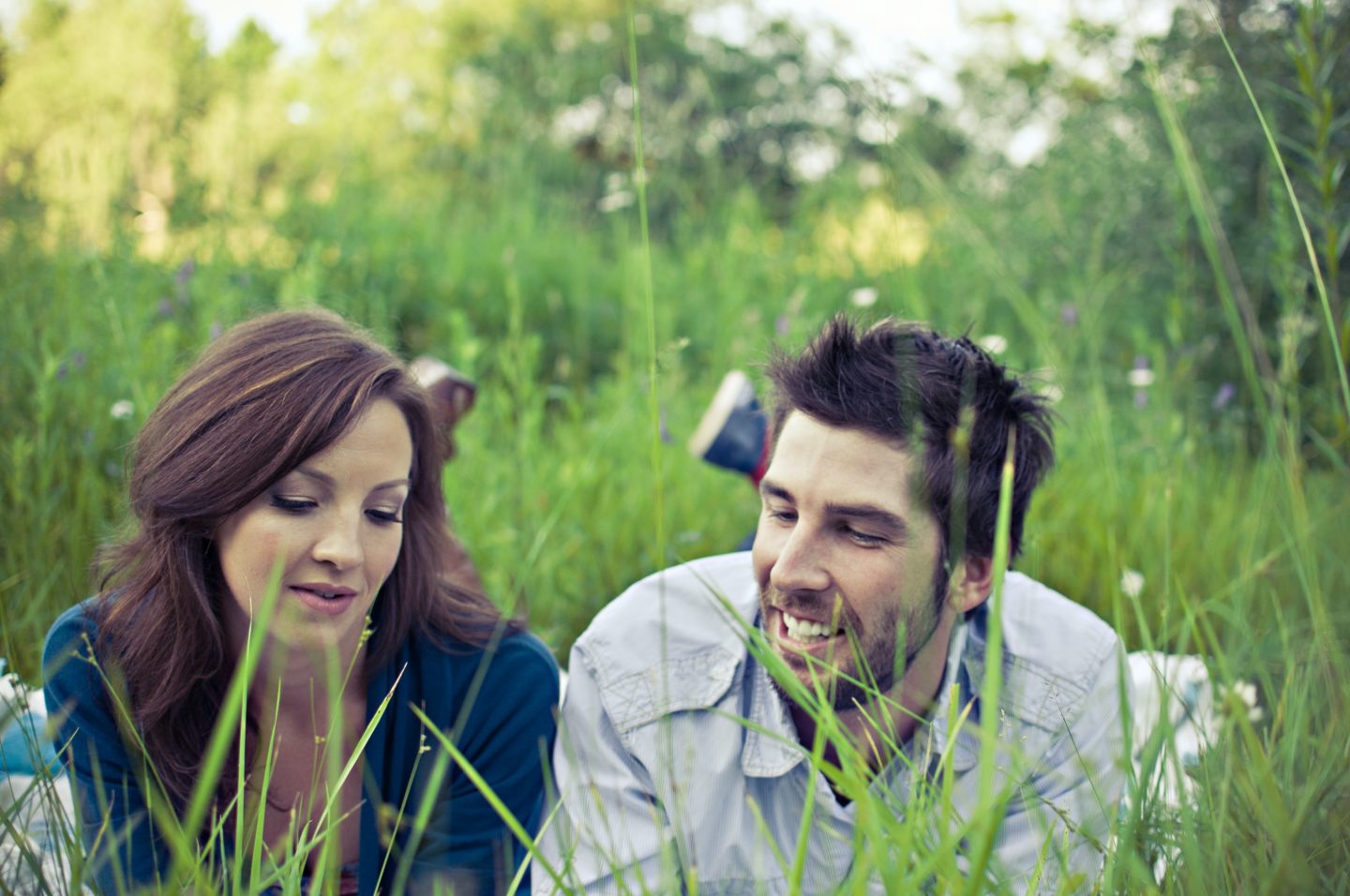 Un couple allongé dans l'herbe discute de leur différence dans leurs besoins de communication