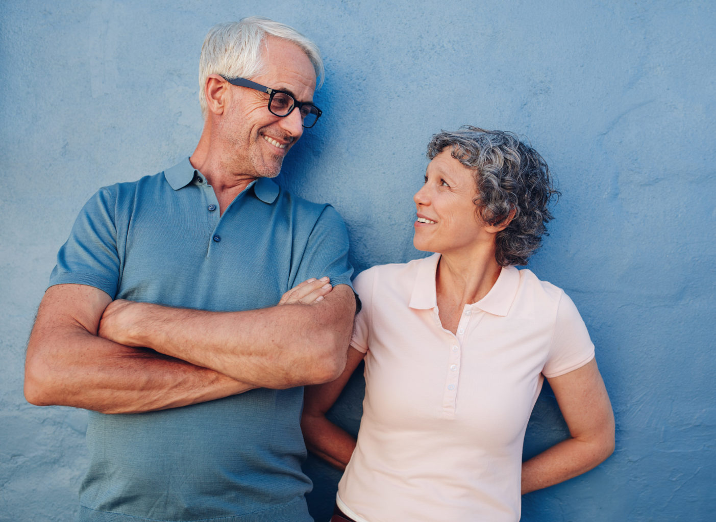 Un homme et une femme âgés se sourient d'une manière complice.