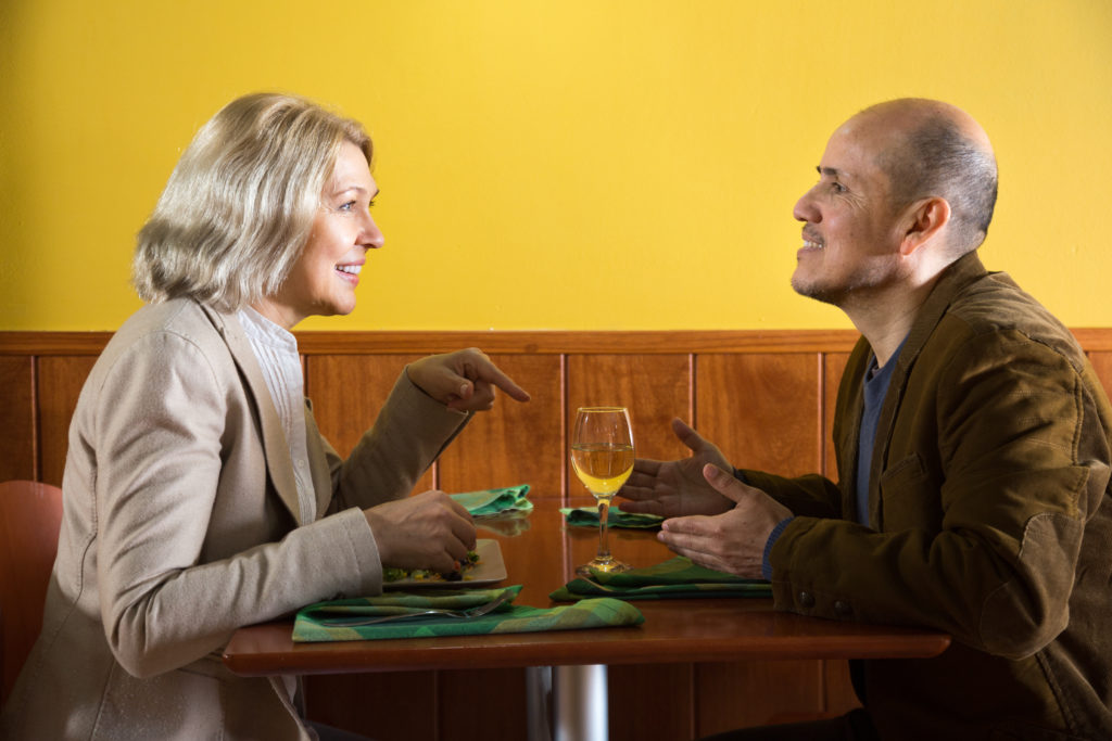 Une femme et un homme de 60 ans discutent au restaurant