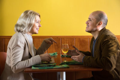 Une femme et un homme âgés discutent avec animation dans un restaurant. Mais qui paiera l'addition ?