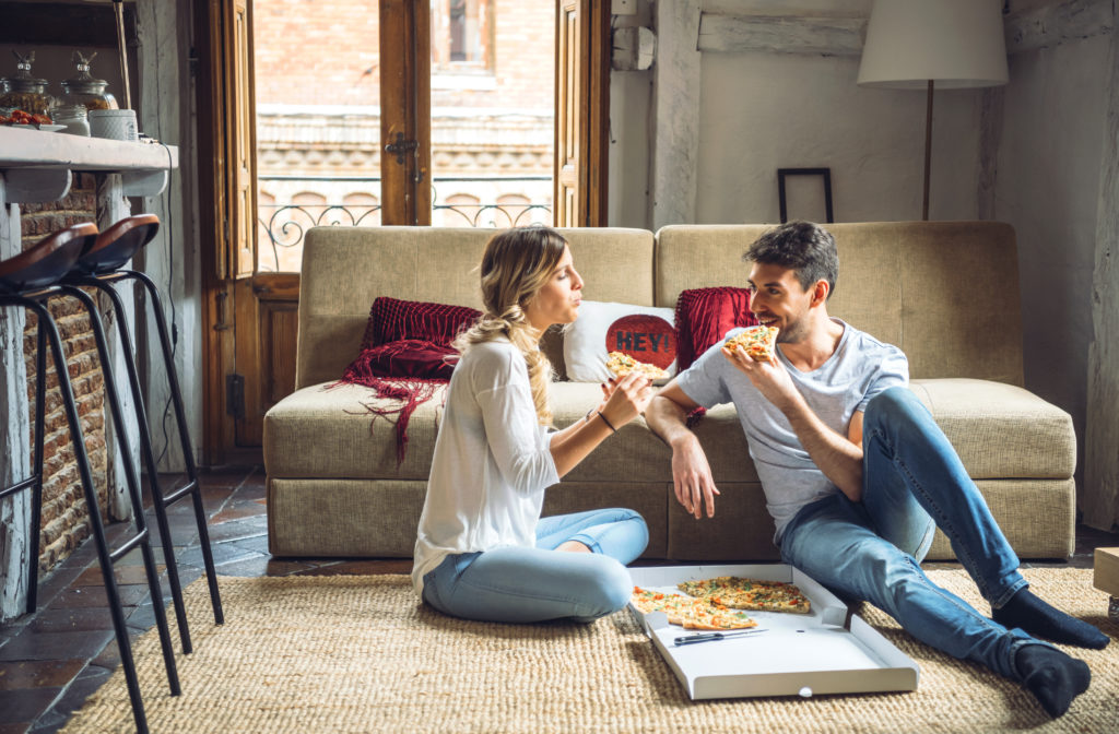 Une femme et un homme mangent une pizza dans un carton