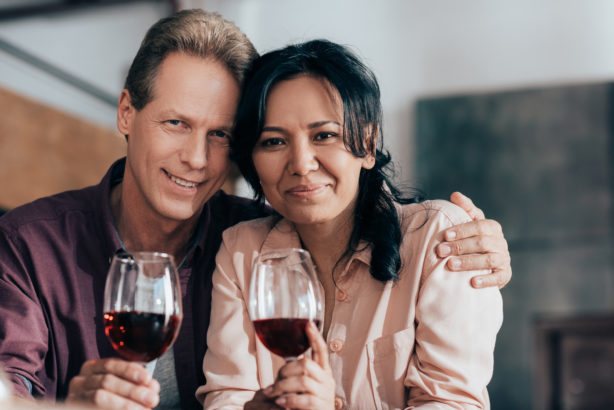 Un homme et une femme, tendrement l'un contre l'autre, boivent du vin chez eux.