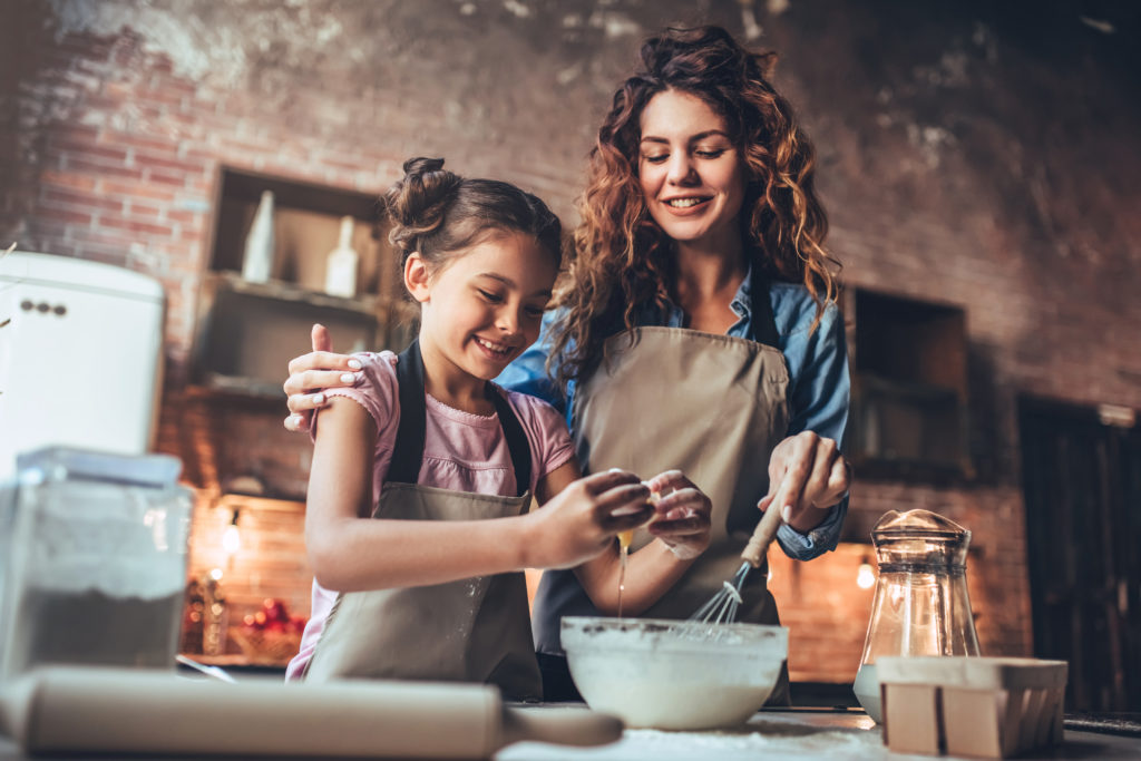 Une femme aide sa fille de douze ans à faire la cuisine