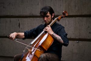 Un homme joue du violoncelle avec sérieux.
