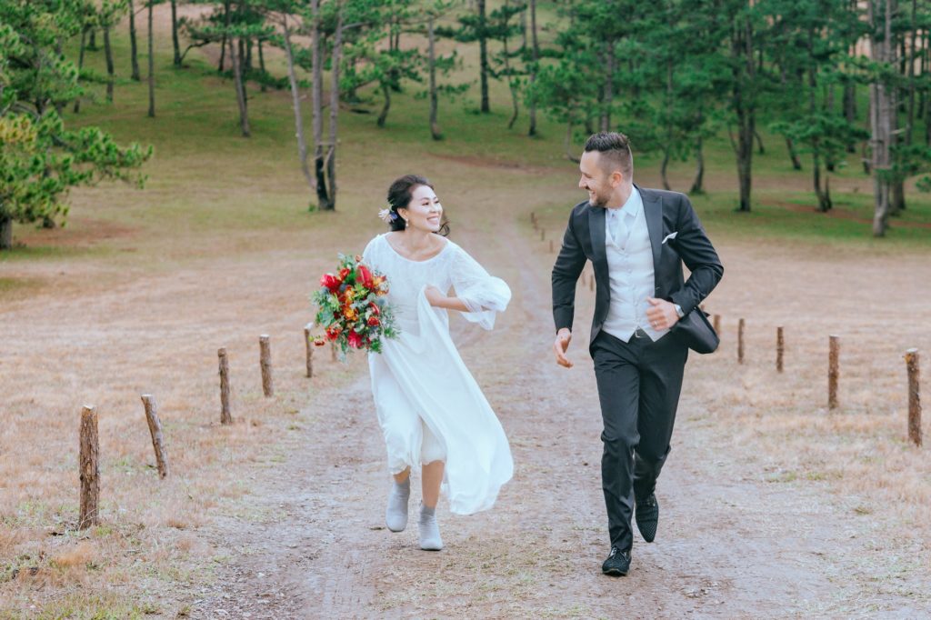 Deux jeunes mariés courent ensemble et se sourient